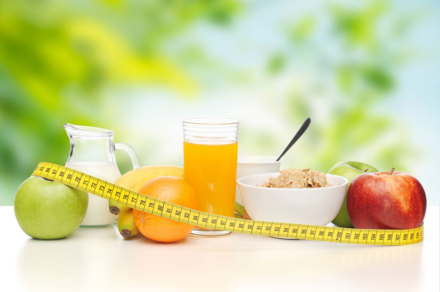 Morgenmad med et målbånd rundt om frugterne, juice, mælk og cornflakes