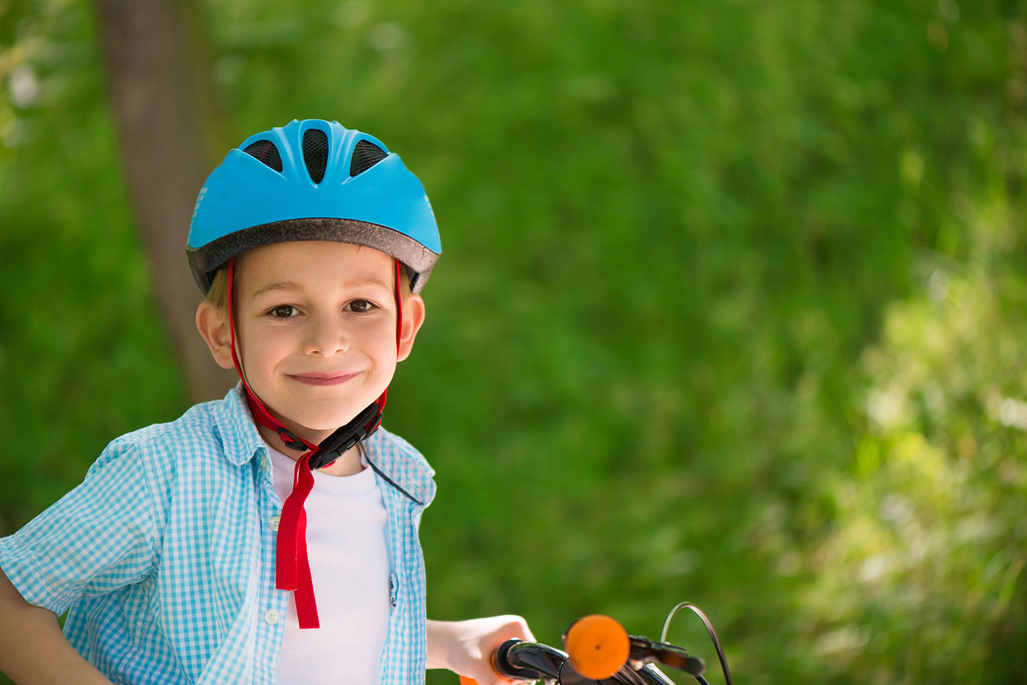 Dreng med en cykel og en blå cykelhjelm på hovedet