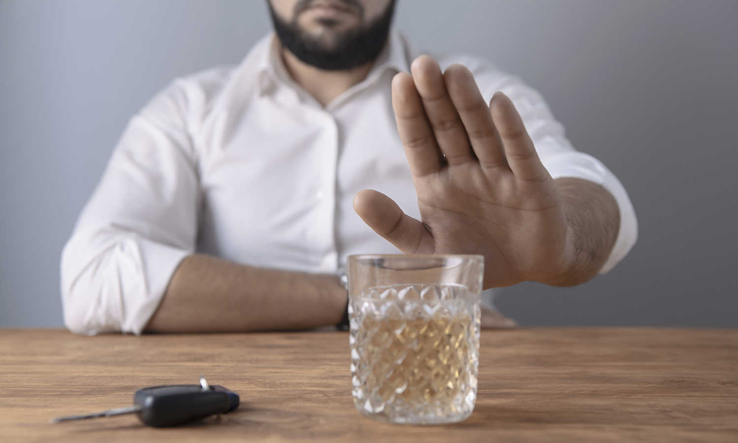 Mand der signalerer med hånden at han afviser et glas whisky
