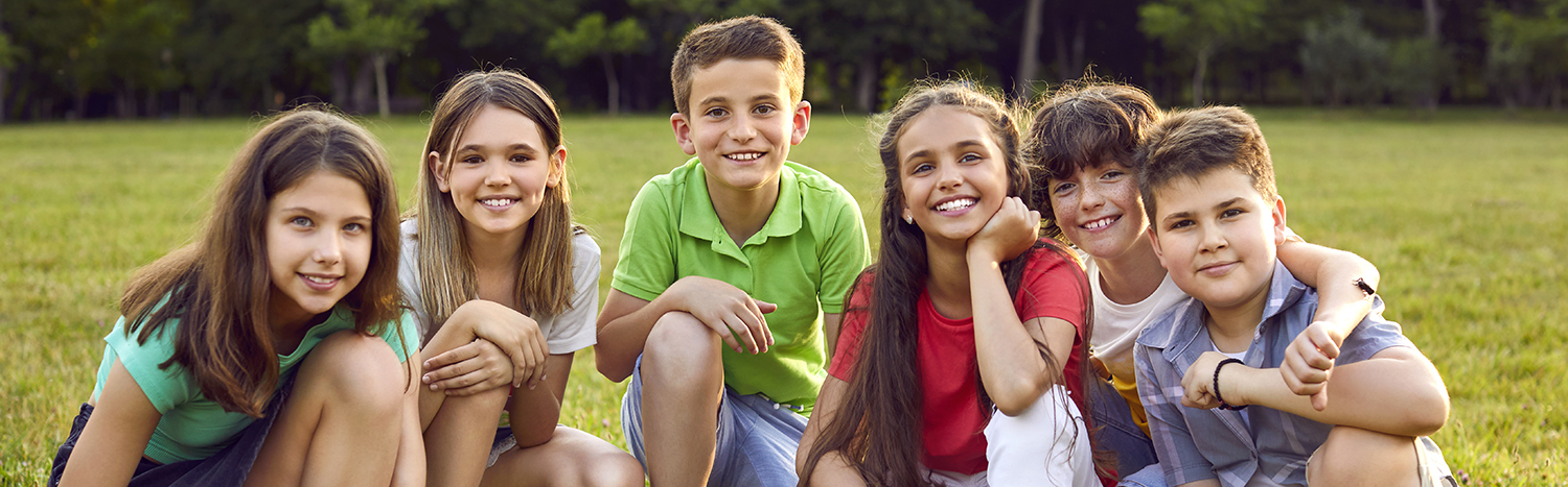 Seks børn sidder på græsplæne