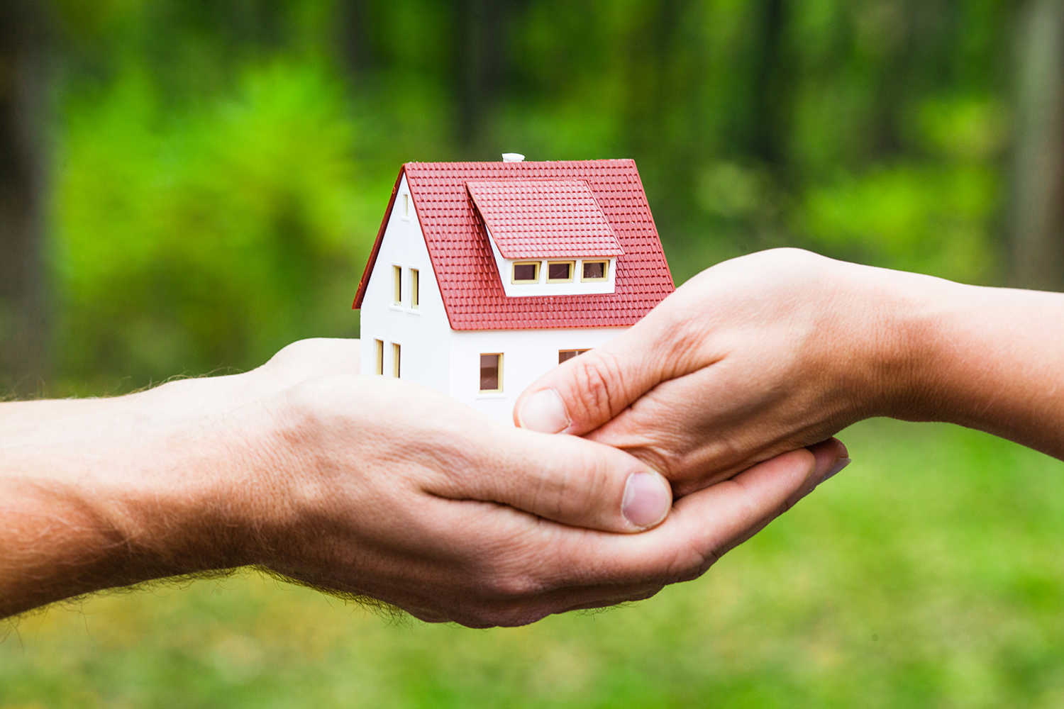 Hænder der holder under et hus